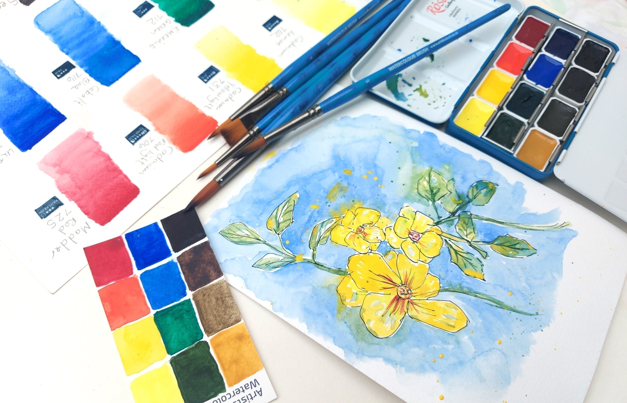 watercolour painting of yellow flowers with brushes and colour charts