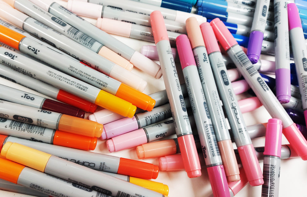 Multiple Copic coloured Ciao Markers piled up on top of each other.