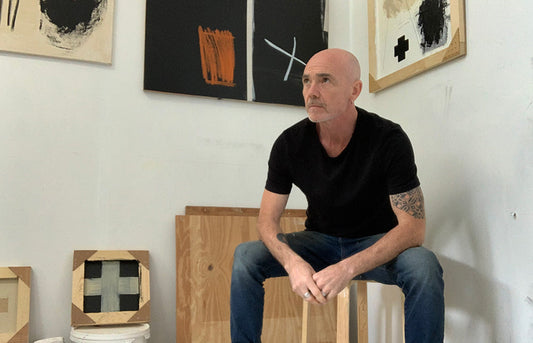 Artist Mark Burrell sat in his studio surrounded by his artwork.