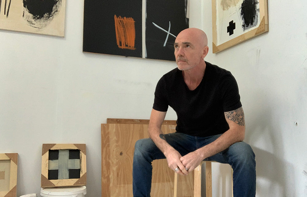 Artist Mark Burrell sat in his studio surrounded by his artwork.