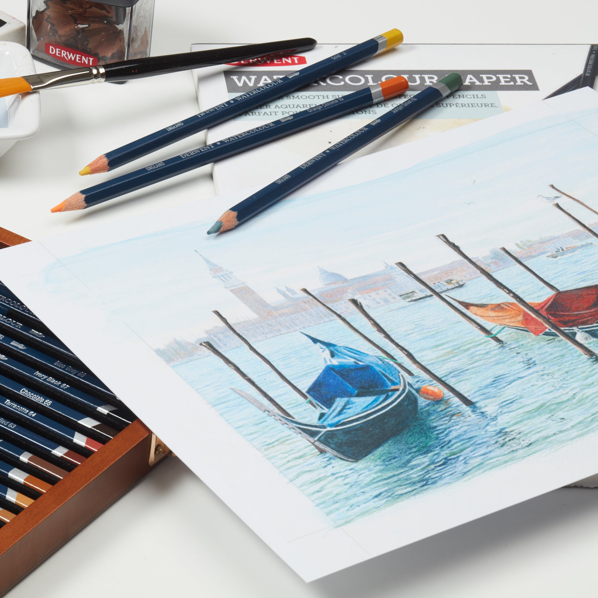 Derwent watercolour pencils on a piece of watercolour paper with a boat painting.