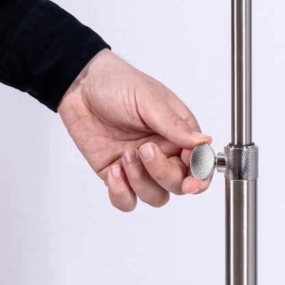Hand adjusting a silver knob on a metallic stand against a white background